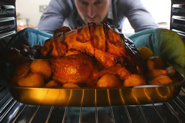 Man putting turkey in oven