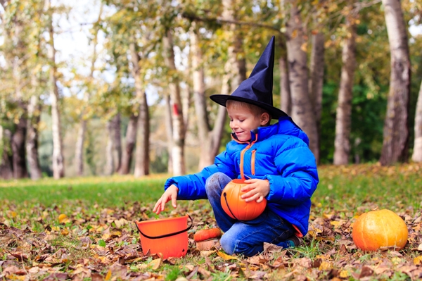 Young boy playing in leaves ready for halloween