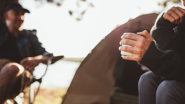 Sitting beside a campfire holding mug