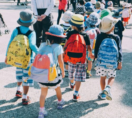 kids wearing backpacks walking into school